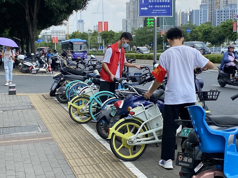 图2：学生第二党支部党员在大学东路整理摆放路边乱停放的共享单.jpg